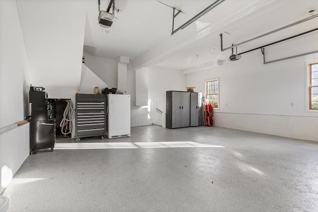 garage with freestanding refrigerator and a garage door opener