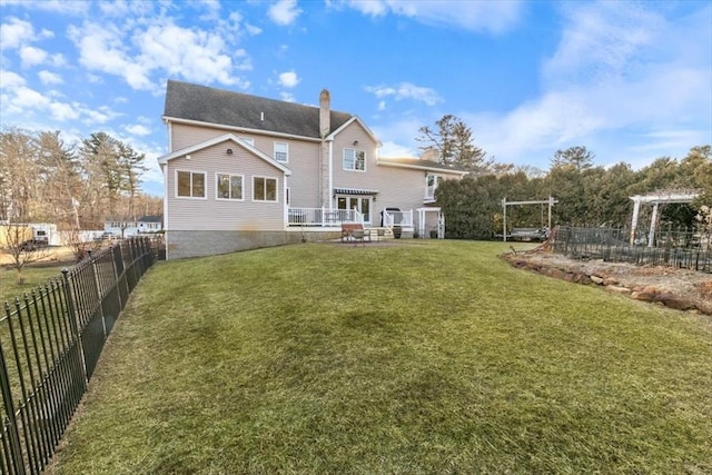 rear view of property featuring a yard, a fenced backyard, and a chimney