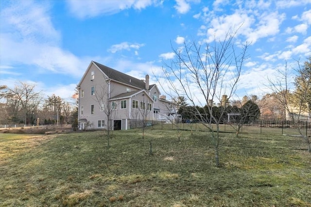 view of home's exterior featuring a lawn, a chimney, and fence