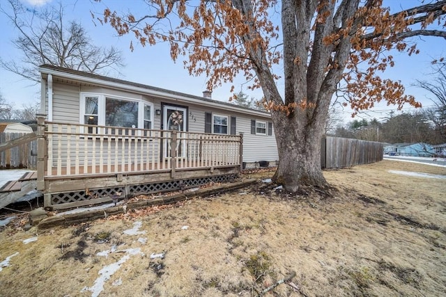 ranch-style home with a chimney, fence, and a deck