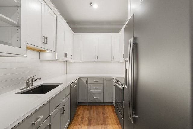 kitchen featuring a sink, wood finished floors, gray cabinets, and stainless steel appliances