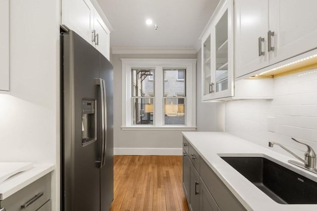 kitchen with backsplash, light countertops, stainless steel refrigerator with ice dispenser, and a sink