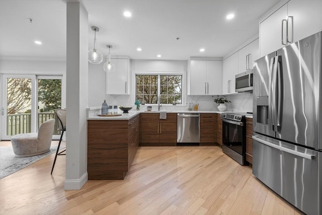 kitchen with white cabinetry, appliances with stainless steel finishes, decorative light fixtures, and dark brown cabinets