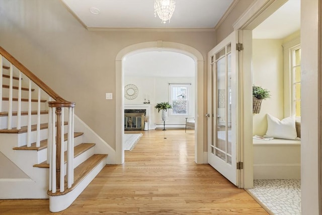 interior space with crown molding, light wood-type flooring, and baseboard heating