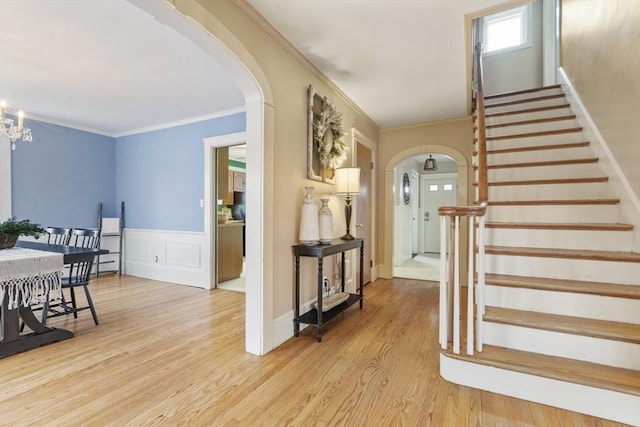 entrance foyer with light hardwood / wood-style floors, an inviting chandelier, and ornamental molding