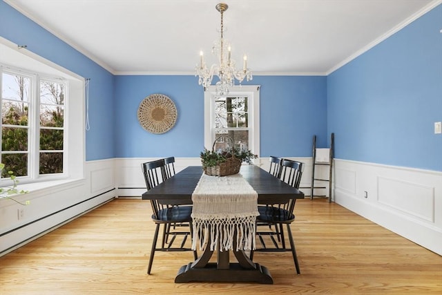 dining area featuring a notable chandelier, light wood-type flooring, ornamental molding, and a baseboard radiator