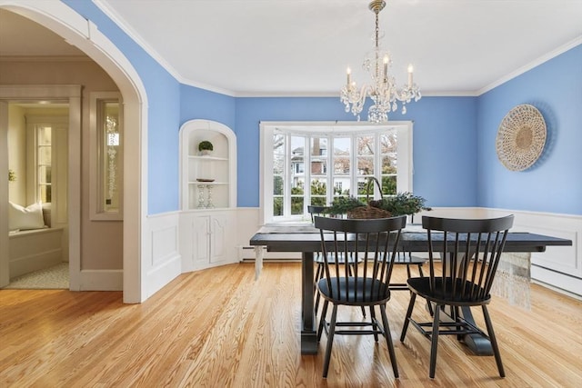 dining room featuring built in features, a baseboard heating unit, a notable chandelier, light hardwood / wood-style floors, and ornamental molding