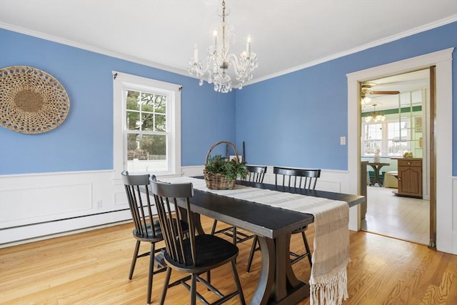 dining space with ceiling fan with notable chandelier, a baseboard heating unit, light wood-type flooring, and ornamental molding