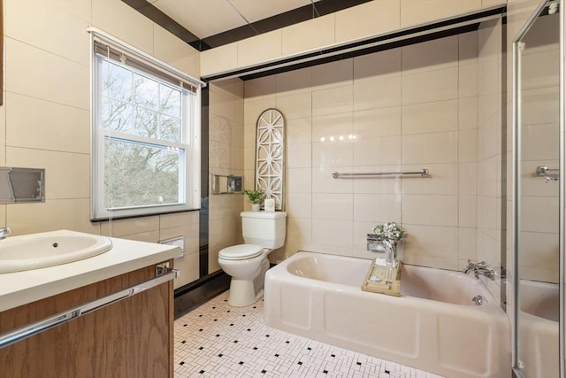 bathroom with a tub to relax in, vanity, tile walls, tile patterned flooring, and toilet