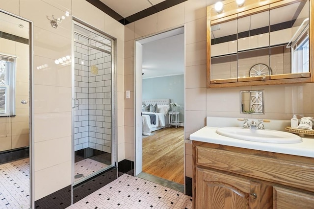 bathroom featuring tile patterned flooring, vanity, tile walls, and walk in shower