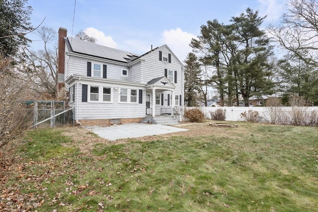 rear view of house featuring a lawn, solar panels, and a patio