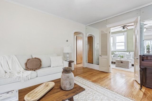 living room featuring light hardwood / wood-style flooring, ceiling fan, and ornamental molding