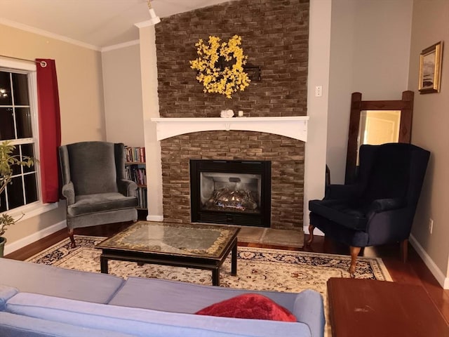 sitting room featuring a large fireplace, ornamental molding, wood finished floors, and baseboards