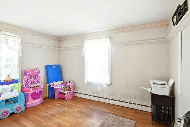 game room with a baseboard heating unit and hardwood / wood-style floors