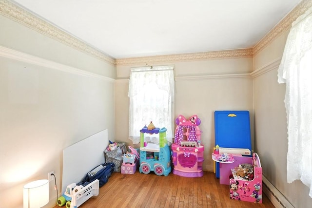 playroom featuring wood-type flooring and a baseboard heating unit