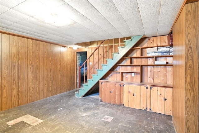 finished below grade area with stairs, tile patterned floors, and wood walls