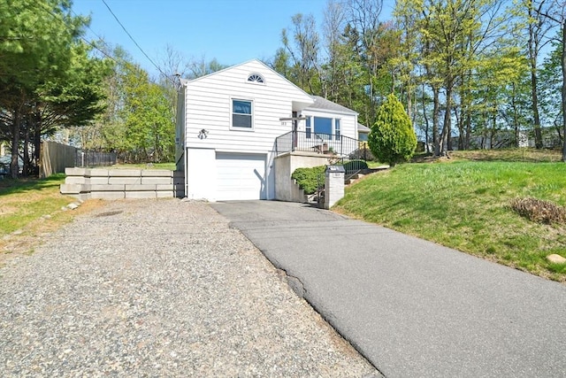 view of front of property with an attached garage, a front lawn, aphalt driveway, and fence