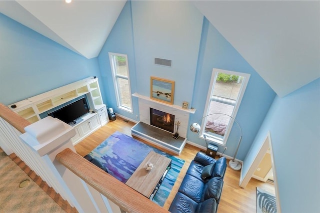26 Crosswinds Way, Falmouth, MA 02536 - living room featuring a warm lit fireplace, high vaulted ceiling, visible vents, baseboards, and wood finished floors