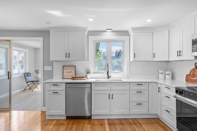 kitchen featuring appliances with stainless steel finishes, a healthy amount of sunlight, a sink, and tasteful backsplash