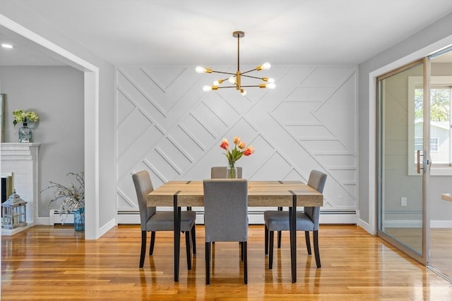 dining room featuring baseboards, a baseboard heating unit, a decorative wall, and a notable chandelier