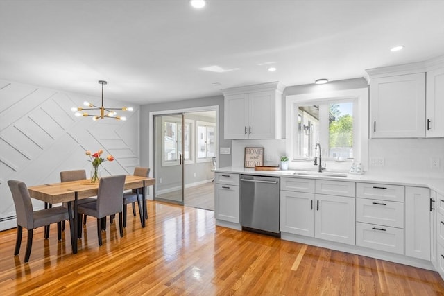 kitchen featuring dishwasher, a sink, light countertops, a notable chandelier, and light wood-style floors