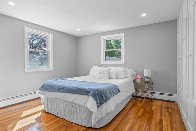 bedroom featuring recessed lighting, a baseboard heating unit, and wood finished floors