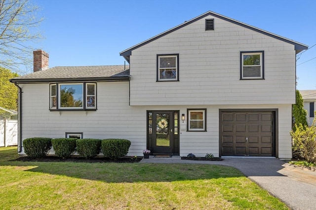 tri-level home with a front lawn, roof with shingles, a chimney, an attached garage, and driveway