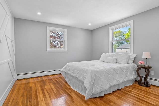 bedroom with a baseboard radiator, baseboard heating, recessed lighting, and wood finished floors