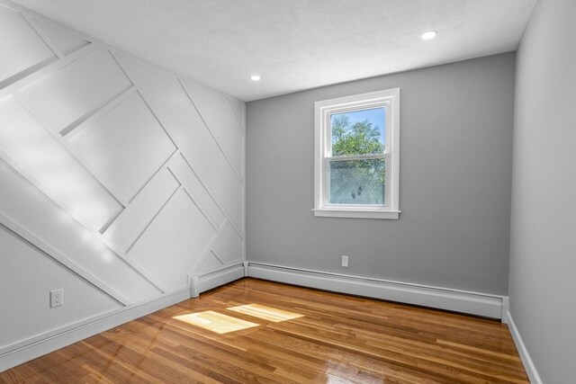 empty room with recessed lighting, baseboards, a baseboard heating unit, and wood finished floors