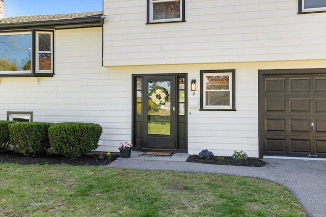 property entrance featuring a lawn and a garage