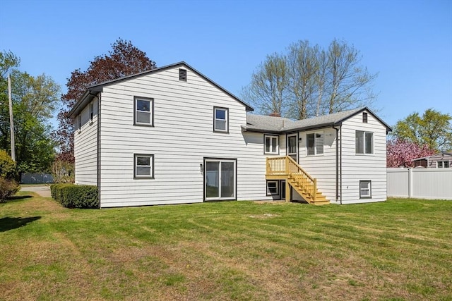 back of house featuring a lawn, fence, and a shingled roof