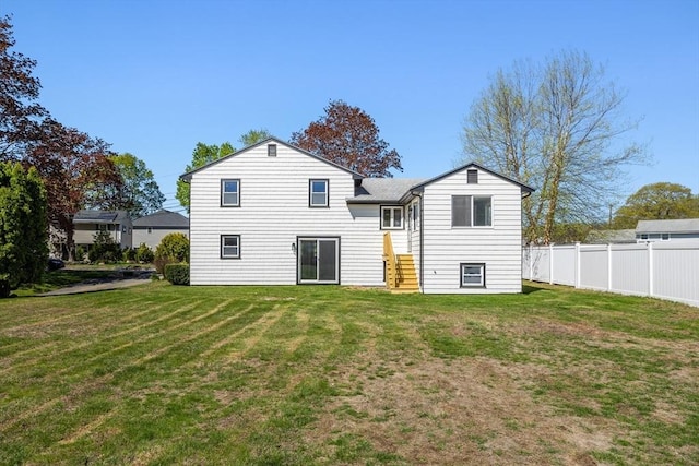 rear view of house featuring a yard and fence