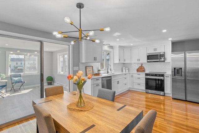 dining space with recessed lighting, baseboards, a notable chandelier, and light wood finished floors