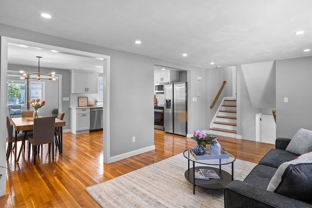 living area with stairs, recessed lighting, and light wood-style flooring