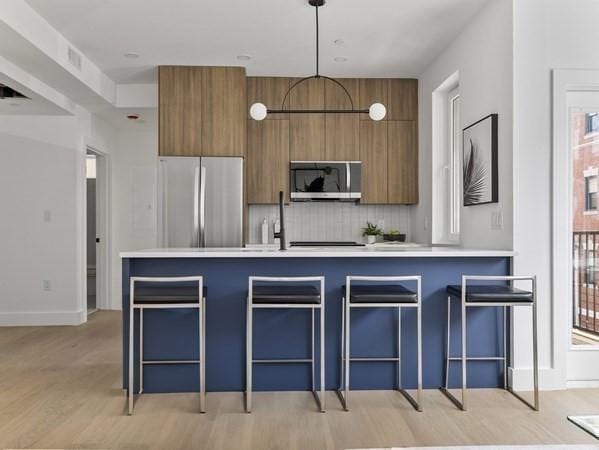 27 Dixwell Unit 8, Boston, MA 02119 - kitchen featuring stainless steel appliances, brown cabinets, modern cabinets, and light countertops