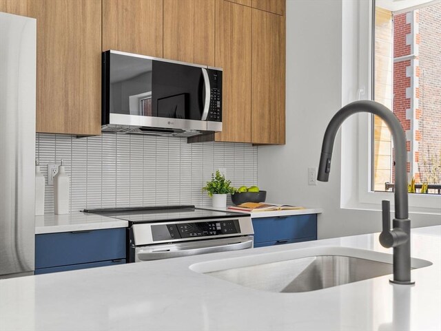 27 Dixwell Unit 8, Boston, MA 02119 - kitchen featuring stainless steel appliances, light countertops, backsplash, modern cabinets, and brown cabinetry
