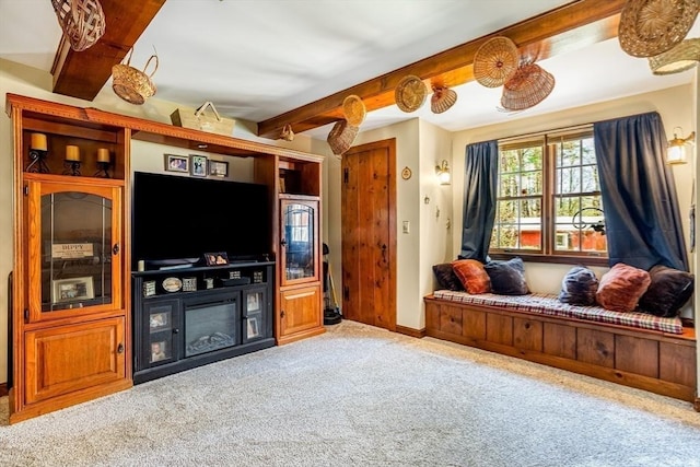 living area with baseboards, beam ceiling, and carpet