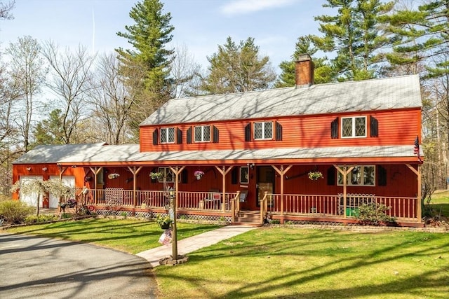 view of front of house with covered porch, a chimney, and a front lawn