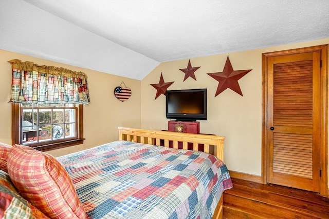 bedroom with wood-type flooring, baseboards, and lofted ceiling