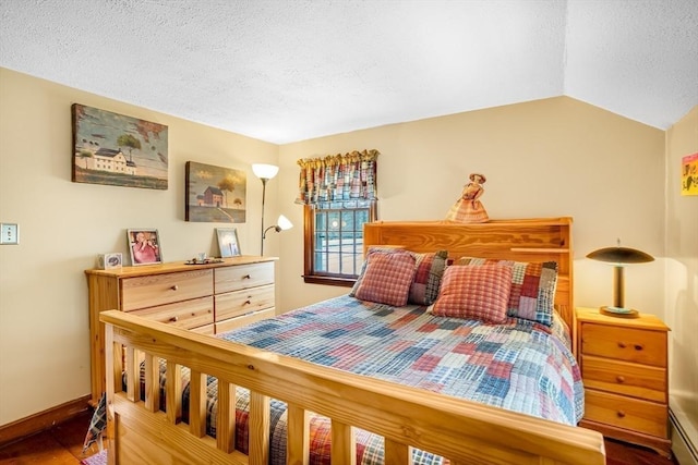 bedroom featuring a textured ceiling, vaulted ceiling, baseboards, and wood finished floors