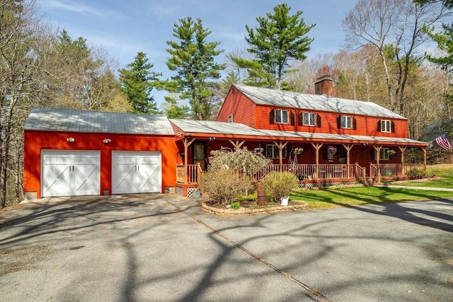 view of front of house featuring a garage, a chimney, a porch, and aphalt driveway