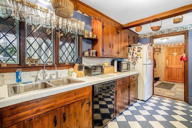 kitchen with a sink, light floors, freestanding refrigerator, black dishwasher, and a toaster