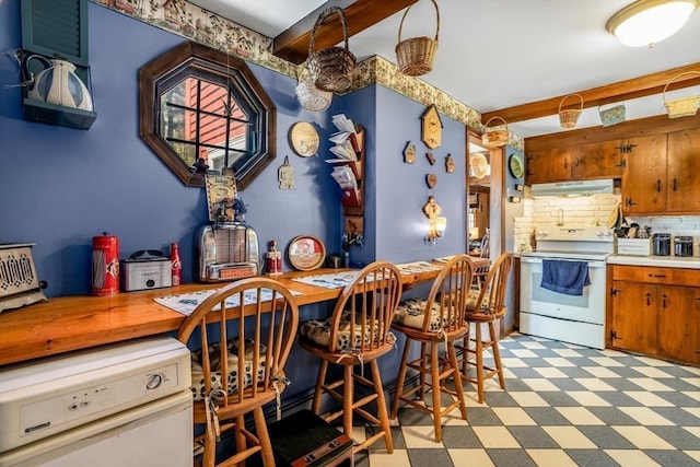 kitchen with decorative backsplash, light floors, light countertops, under cabinet range hood, and electric stove