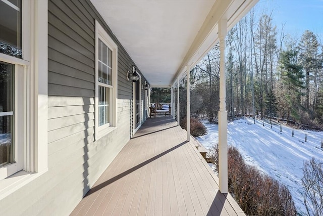 snow covered deck featuring covered porch