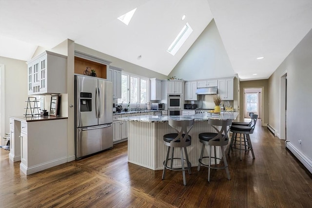 kitchen with a skylight, a breakfast bar area, a center island, light stone counters, and stainless steel appliances