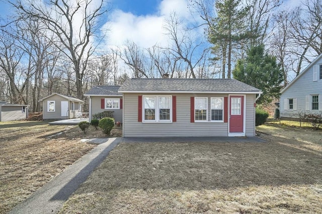 ranch-style home featuring a front yard and a storage unit