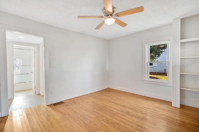 unfurnished room with ceiling fan, a textured ceiling, and light hardwood / wood-style flooring