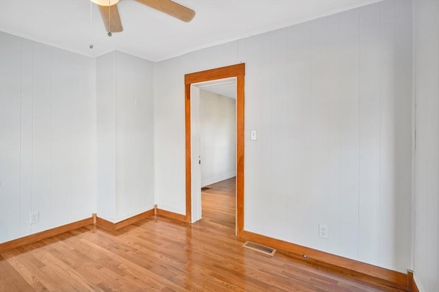 empty room featuring hardwood / wood-style flooring, ceiling fan, and wood walls