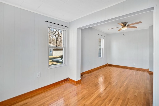 spare room with wooden walls, light hardwood / wood-style flooring, ceiling fan, and ornamental molding