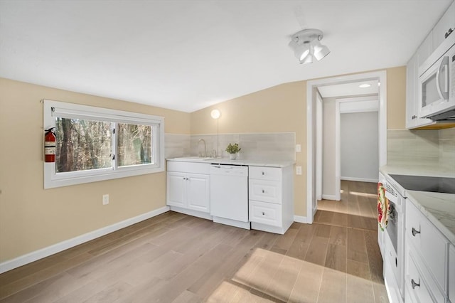 kitchen with white cabinetry, sink, light hardwood / wood-style floors, lofted ceiling, and white appliances